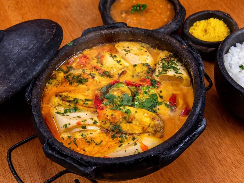 Moqueca de peixe na panela de barro, com arroz e farofa ao lado